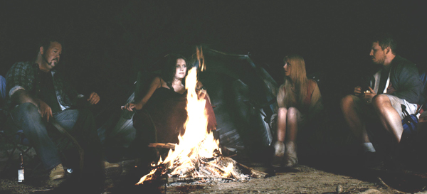 Mick (Sam Coward), Jason (Dean Kirkright), Natasha (Tara Reid) and Melanie (Allira Jaques) sit at campfire as Mick tells the story of Charlie's Farm