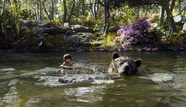 Mowgli (Neel Sethi) swims across a river with Baloo (Bill Murray)